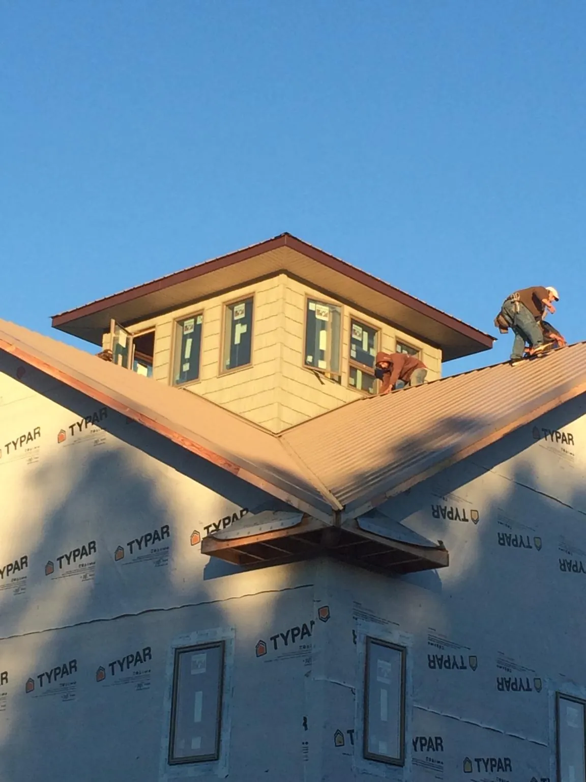 Roofers working around a rooftop cupola on a new metal roof at sunset — Roof Waterproofing in Bloomfield by Roofing Brothers